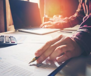 business man pointing his ideas and writing business plan at workplace,man holding pens and papers, making notes in documents, on the table